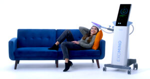 Woman laying on blue couch smiling comfortable with EXOMIND device on her head