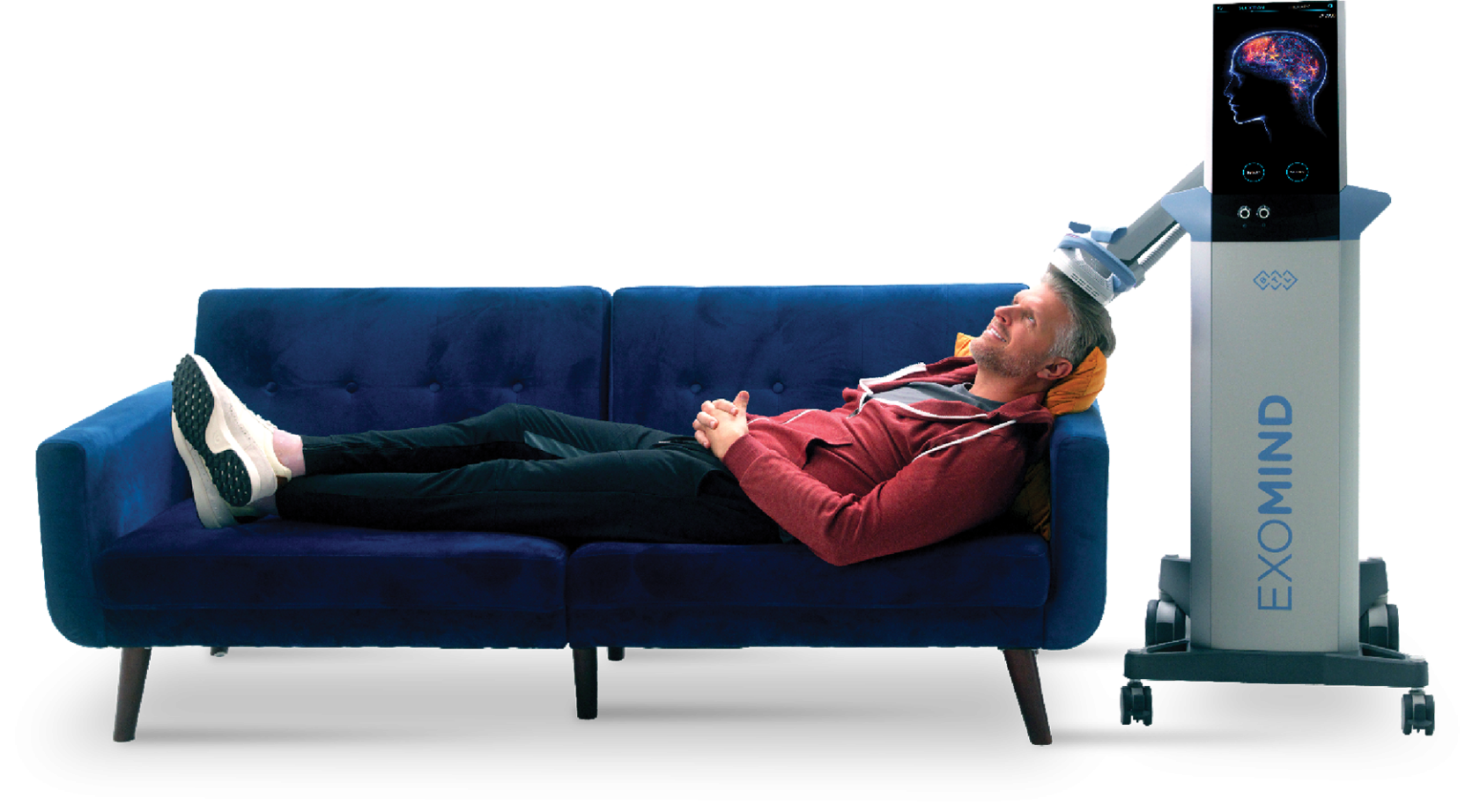 Man lying comfortably, smiling on a blue couch with BTL Exomind on his head