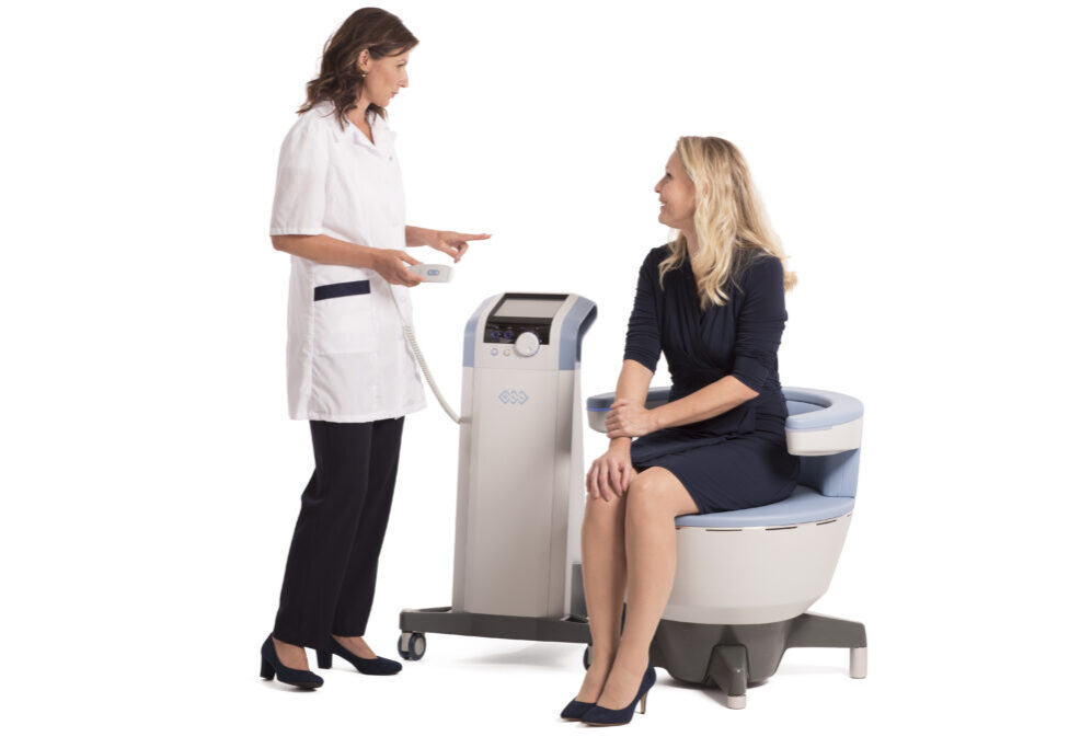 Emsella chair with a patient sitting comfortably and clinician standing beside them Miramont Wellness Centers